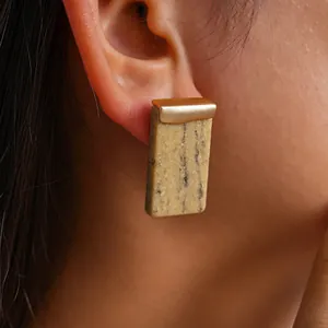 Detaillierte Makroansicht eines rechteckigen Harz-Ohrrings mit goldener Metallverzierung