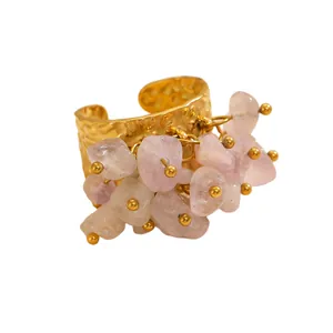 Close-up view of a Bohemian hammered gold-plated ring with dangling pink natural stone charms