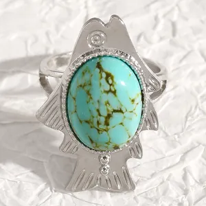 Close-up view of a vintage silver fish-shaped ring featuring an oval turquoise stone inlay