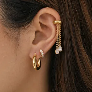 Detailed view of gold stainless steel tassel ear cuff and hoop earrings on model's ear