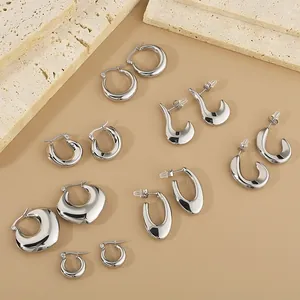 Collection of polished silver stainless steel geometric hoop and drop earrings.
