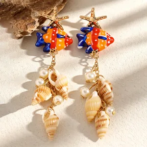 Vue détaillée des boucles d'oreilles poisson en céramique avec coquillages et perles