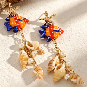 Gros plan de boucles d'oreilles poisson tropical avec coquillages et perles