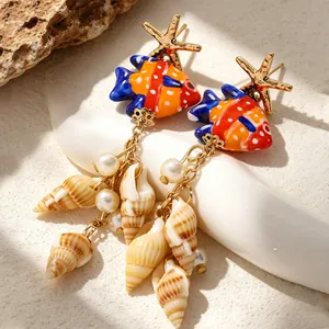 Détail de boucles d'oreilles style océan avec poissons en céramique et coquillages