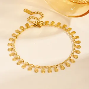 Vue macro d'un bracelet en acier inoxydable plaqué or avec breloques gouttes d'eau soleil