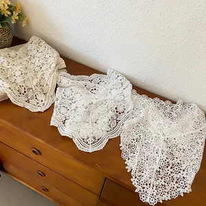 Detailed view of three white hollow-out crochet lace triangle scarves on dresser