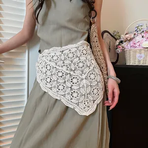 Detailed close-up of white hollow-out crochet lace triangle scarf worn as a waist accessory