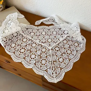 Macro view of delicate white hollowed-out crochet lace pattern on triangular scarf