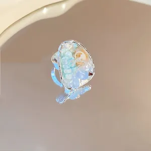 Macro view of a vintage style open ring with blue beads and a small shell detail.