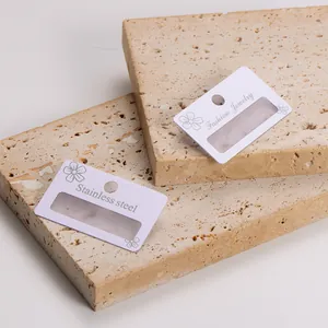 Close-up of white PVC earring display cards with frosted hollow design on stone blocks
