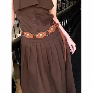 Close-up of a Bohemian brown woven belt with metal rings and studs in Maillard style