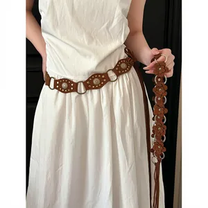 Detail of Bohemian brown belt with floral cutouts and vintage rivets on white dress