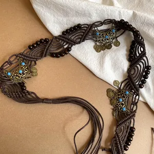 Detailed macro view of bohemian woven belt with wooden beads and crescent charms