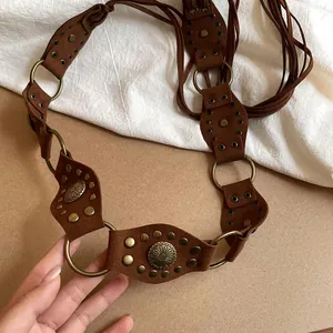 Detailed view of bohemian brown suede waist belt with vintage floral studs and bronze rings