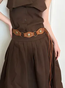 Detail of vintage Bohemian suede belt with metal rings and long fringes on brown dress