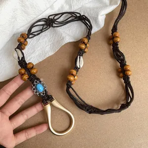 Detail of Bohemian brown braided belt with wooden beads, shells and turquoise charm.