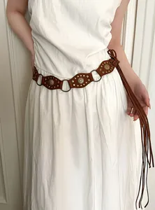 Detail of Bohemian brown suede belt with bronze studs and long tassels on white dress