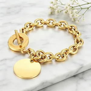 Close-up of gold titanium steel chunky O-link bracelet with round charm on marble.