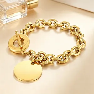 Close-up of gold titanium steel O-link bracelet with toggle clasp and round charm.