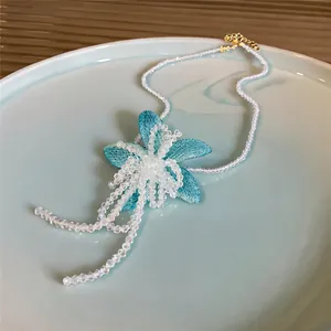 Close-up of blue mesh flower necklace with shimmering bead tassels on a ceramic plate