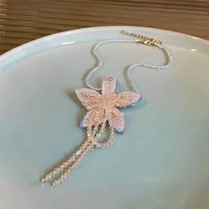 Close-up of French-style floral beaded necklace with elegant tassels and pink woven petals