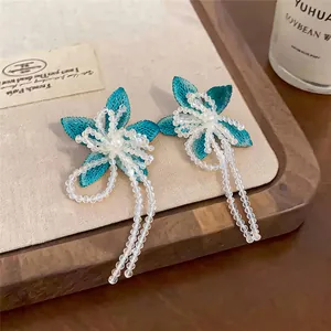 Close-up of elegant turquoise flower earrings with delicate white beaded tassels
