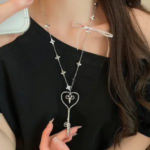 Vista detallada de un collar con colgante de llave de corazón y un lazo blanco.