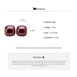 Detail of burgundy glossy cube stud earrings with silver needles and alloy material