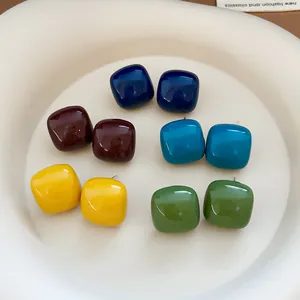 Macro view of colorful square enamel stud earrings in various vibrant shades for women