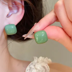 Close-up of green drip oil candy stud earrings showing glossy enamel texture