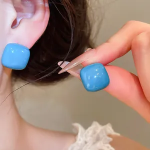 Close-up showing the glossy texture of bright blue sugar bean enamel stud earrings