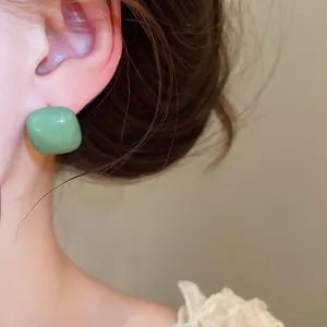 Detailed close-up of vibrant green square enamel stud earrings with premium silver needles.