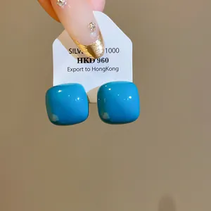 Detail view of vibrant blue square drip oil stud earrings on a display card