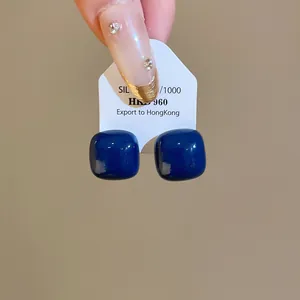 Detailed view of dark blue enamel bean earrings with silver needles on a display card.