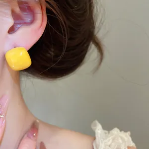 Detailed macro view showing the bright yellow sugar bean stud earring worn on ear