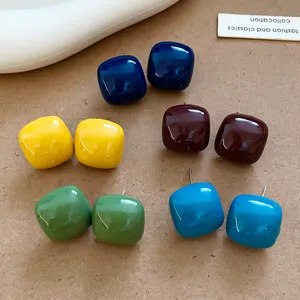 Macro view showing five pairs of colorful square enamel stud earrings in various vibrant shades