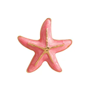 Detailansicht eines rosa Emaille-Seestern-Accessoires mit goldfarbenen Metallkanten.