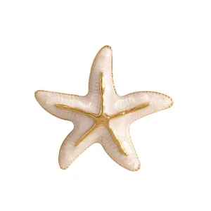 Detaillierte Nahaufnahme einer goldenen Seestern-Brosche mit cremefarbenem Emaille-Dekor.
