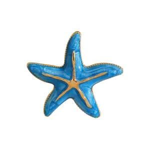 Detailansicht einer leuchtend blauen Seestern-Brosche mit Goldakzenten und Glitzer-Finish.