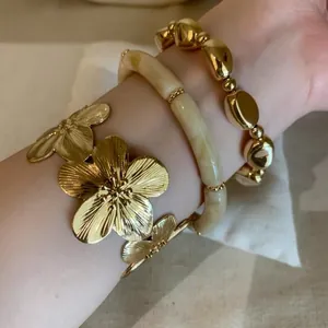 Detailed close-up showing vintage gold floral cuff stacked with elegant beaded bracelets