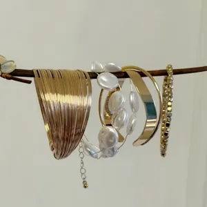 Artistic display of vintage gold stackable bracelet set and pearls on a natural branch