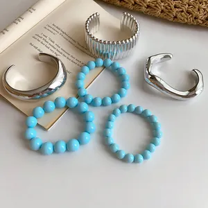 Vintage silver cuff bracelets and blue beaded jewelry set displayed on a book