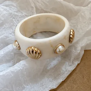 Vintage wide cream acrylic bangle decorated with gold seashell charms and faux pearls