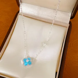 Détail macro d'un collier trèfle à quatre feuilles en argent avec résine bleue et zircon