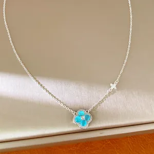 Gros plan d'un collier trèfle en argent avec pétales en résine bleue et zircons étincelants