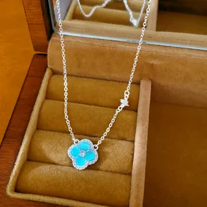 Gros plan d'un collier trèfle bleu avec pendentif papillon en zircon dans son écrin