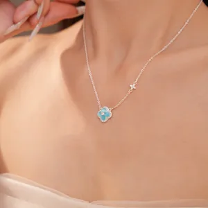 Détail d'un collier en trèfle argenté orné d'une pierre bleu clair et de zircons scintillants.