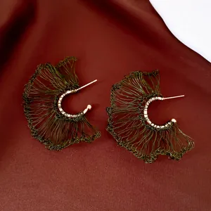 Detalle de pendientes artesanales de alambre tejido en forma de abanico verde y oro