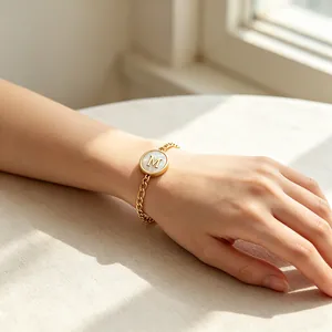 Close-up of a gold stainless steel bracelet with a natural shell letter M charm.