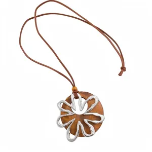 Collar largo con colgante redondo de madera y detalle de flor plateada en blanco.